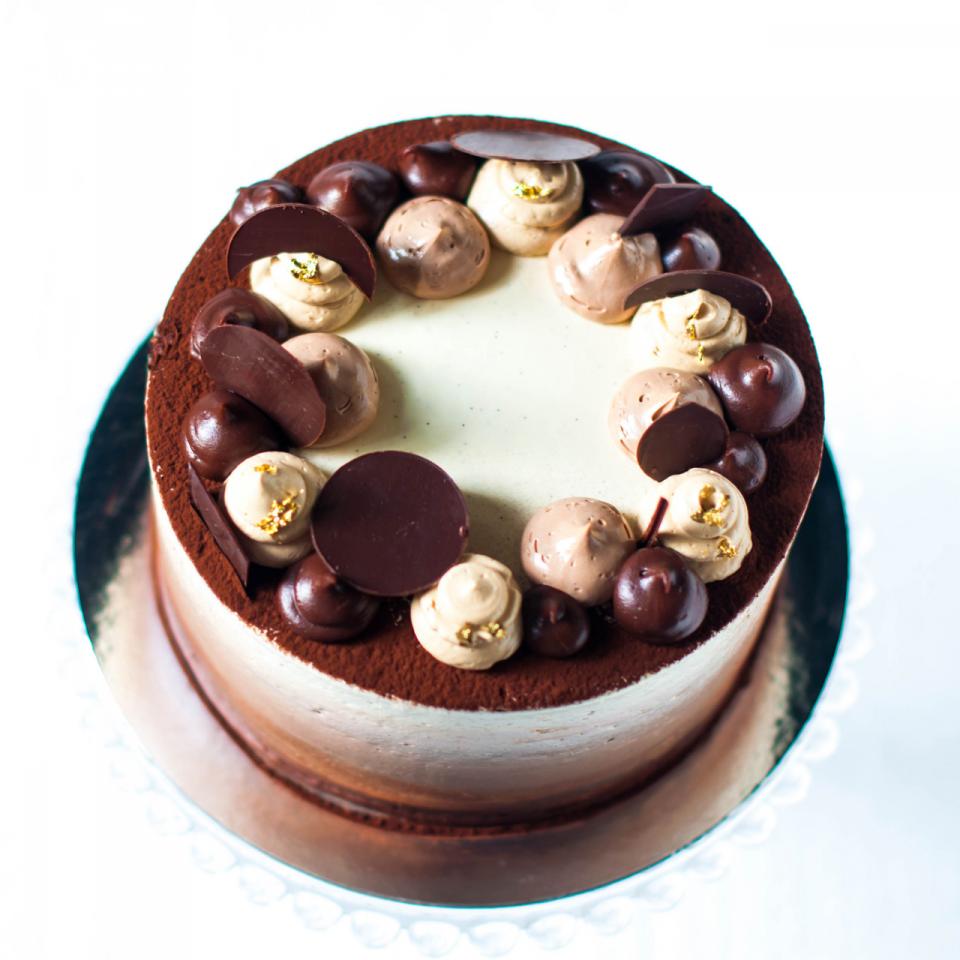 Mocha cake4 layers of light vanilla sponge soaked with coffee syrup filled with whipped coffee ganache. The cake is covered with vanilla, coffee and chocolate buttercream to create a marble effect. The cake is decorated with dusting of cocoa powder, chocolate, coffee and vanilla buttercream and chocolate pieces.